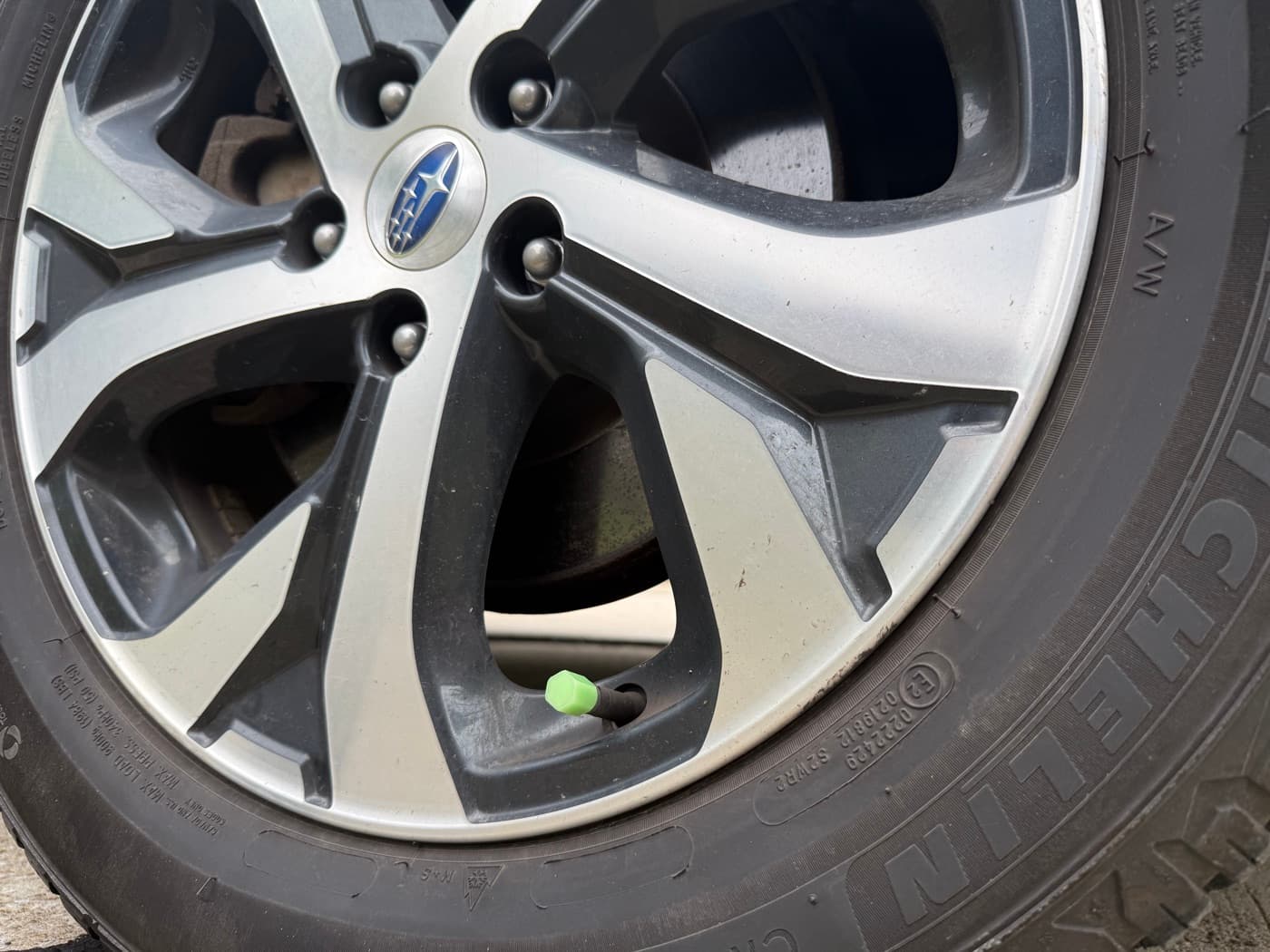 Real VeloGlo valve cap glowing green on a Subaru wheel in daylight